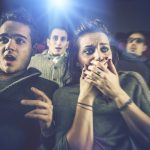 映画館で怖がるカップル